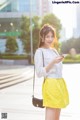 A woman in a yellow skirt is looking at her phone.