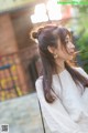 A woman with long brown hair wearing a white shirt.