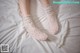 A woman laying on a bed wearing a pair of white socks.