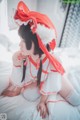 A woman in a red and white outfit sitting on a bed.