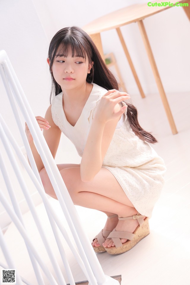 A woman in a white dress crouching down on the stairs.