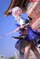 A woman dressed in a blue and white outfit holding a sword.