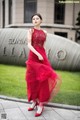 A woman in a red dress standing in front of a building.