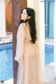 A woman leaning against a wall next to a pool.