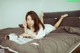 A woman laying on a bed reading a magazine.