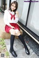 A woman in a school uniform sitting on a ledge.