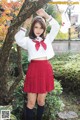 A woman in a red skirt and white shirt posing for a picture.