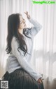 A woman sitting on a window sill in front of a window.