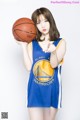 A woman in a blue and yellow uniform holding a basketball.