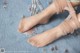 A close up of a woman's feet wearing a pair of nude colored stockings.