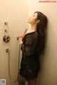 A woman in a black dress standing in a shower.