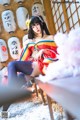 A woman in a kimono sitting on a chair in front of lanterns.