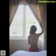 A naked woman sitting on a bed looking out a window.