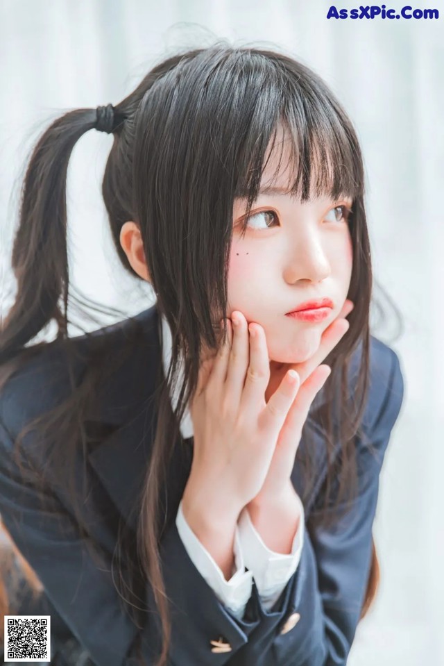 A young woman with long black hair wearing a school uniform.