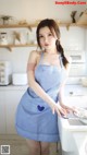 A woman in a blue and white apron standing in a kitchen.