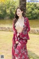 A woman in a red kimono posing next to a palm tree.