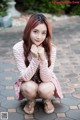 A woman in a pink and white striped dress crouching on the ground.