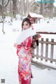 A woman in a red kimono standing in the snow.