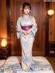 A woman in a blue kimono standing on a bed.