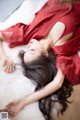 A woman in a red dress laying on a white rug.