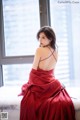 A woman in a red dress sitting on a window sill.