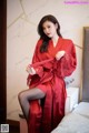 a woman in a red robe sitting on a bed